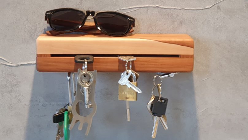 Schlüsselbrett mit Ablage Apfel Sonnenbrille auf einem Holzschlüsselbrett mit mehreren Schlüsseln.