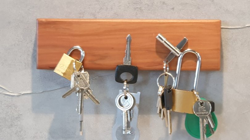 Schlüsselbrett Apfel magnetisch Drei Schlüsselbund mit verschiedenen Schlüsseln und einem Vorhängeschloss an einem Holzbrett.